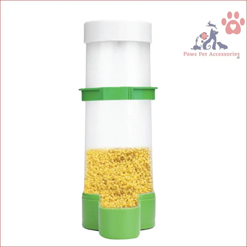 White plastic cage food dispenser with green accents, filled with yellow powder for parrots